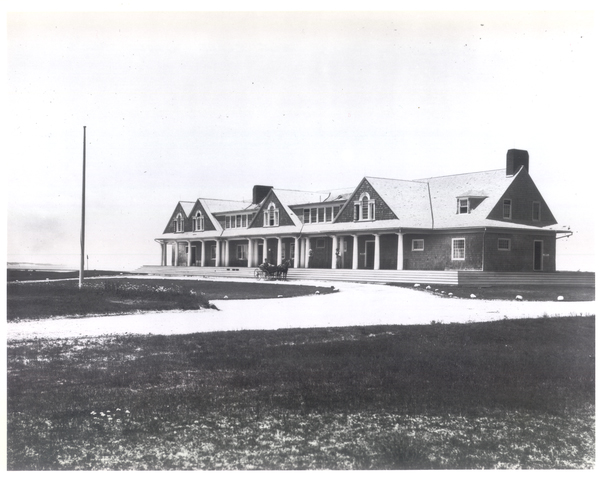 Black and white photograph of the expanded Shinnecock Hills clubhouse with a horse and carriage at the entrance