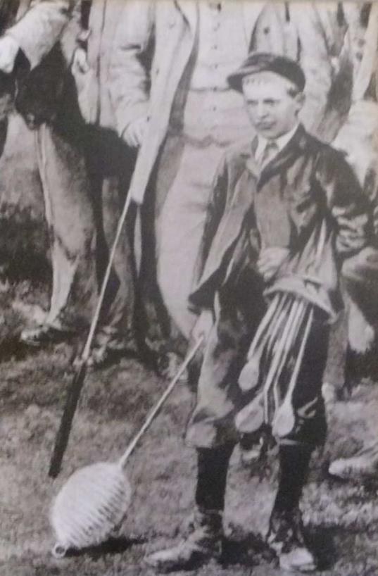 An early photograph showing a young figure beside a golf standard topped with a woven wicker basket, early 1900s