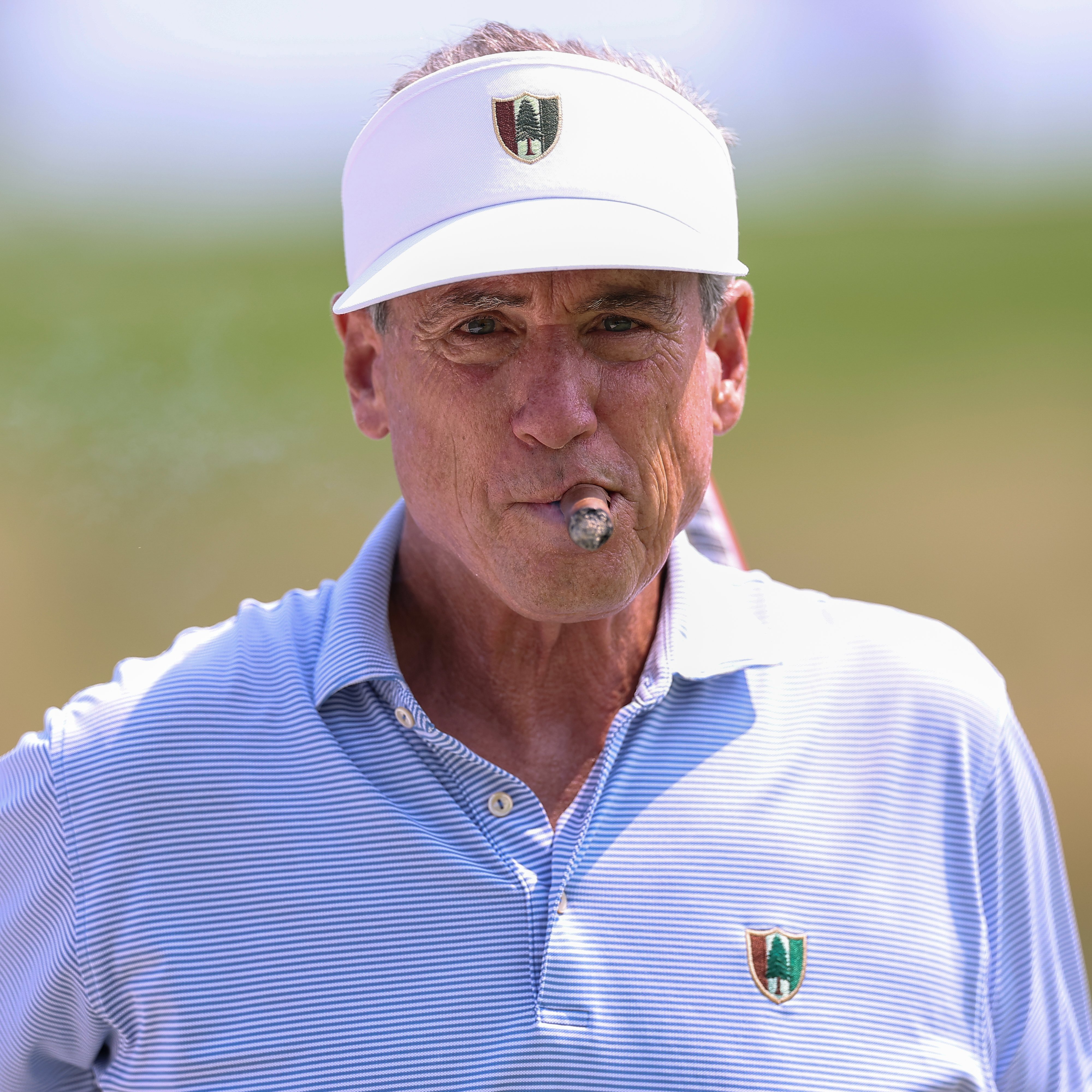 Mike McCoy stands on Merion Golf Club with a cigar, wearing a Pine Valley visor and Seminole polo